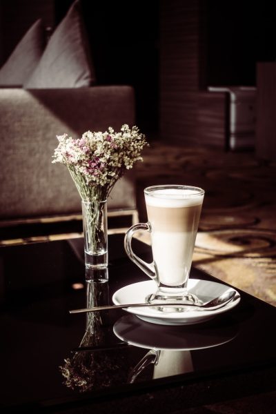 Hot latte coffee cup with vase flower on table - Vintage Filter